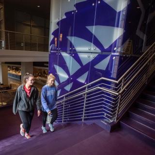 Two girls walk up a staircase in the multi purpose building at TCU's Worth Hills