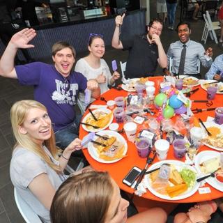 A group of TCU students raise their celebratory purple margaritas at a festive round table