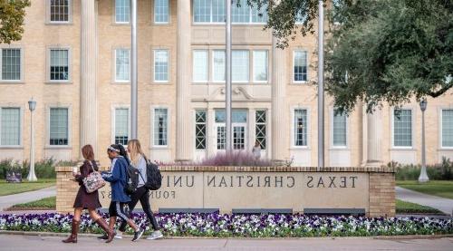 Students walking in a group by TCU sign