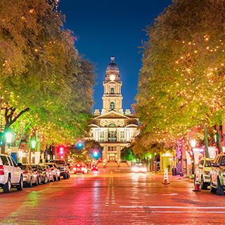 A northerly view at night looking up a downtown street lined with trees adorned with sparkling white lights to the county courthouse